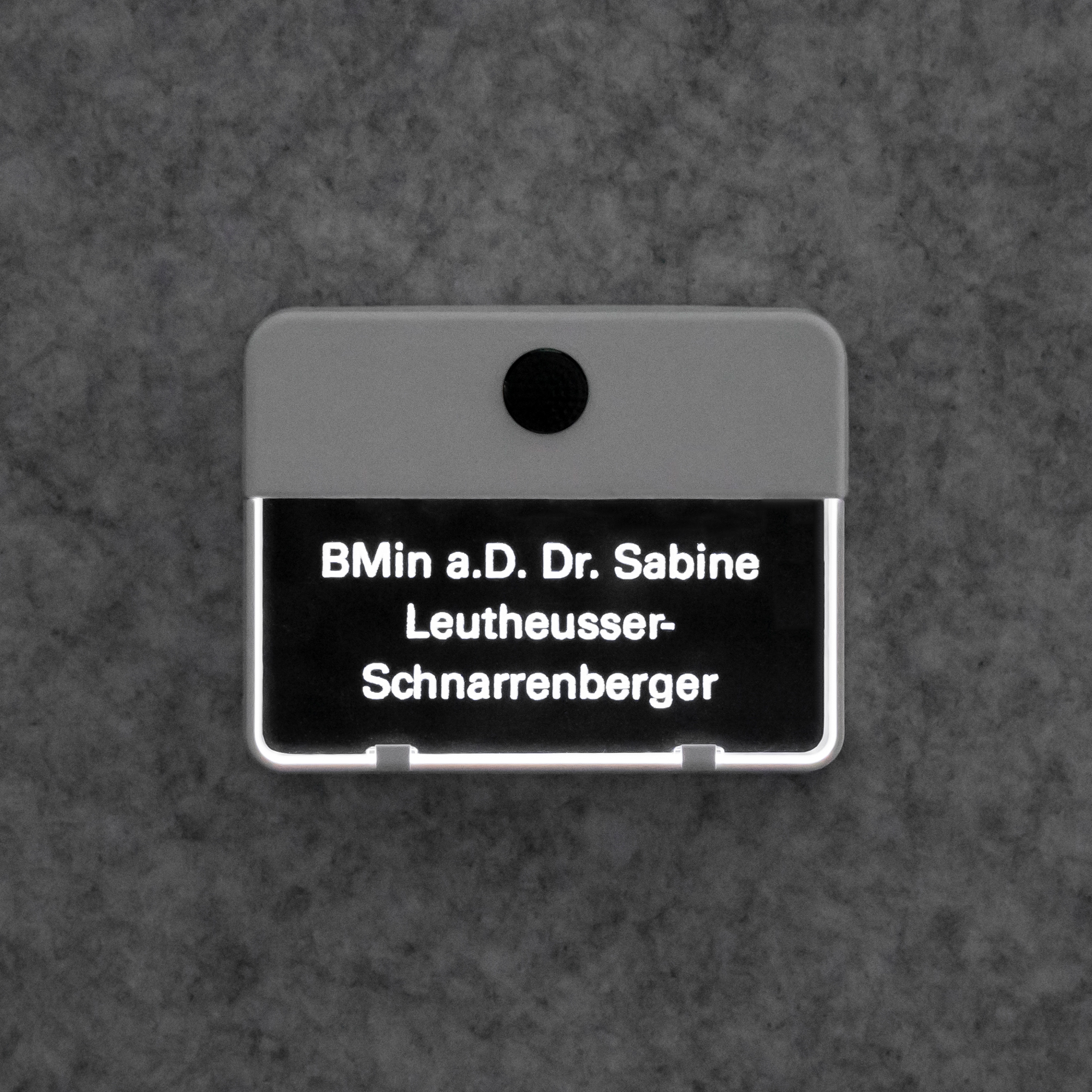 Klingelplatte mit weiß hinterleuchteter Gravur „BMin a.D. Dr. Sabine Leutheusser-Schnarrenberger“, frontal an Wand.